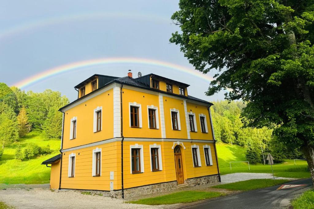 a yellow house with a rainbow in the background at Celnice pod Sněžníkem-Nová Seninka in Staré Město