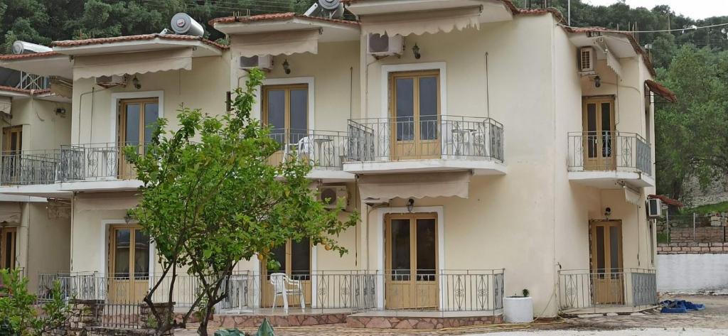 a large white building with balconies and a tree at Ariadni Fountas Studios in Parga