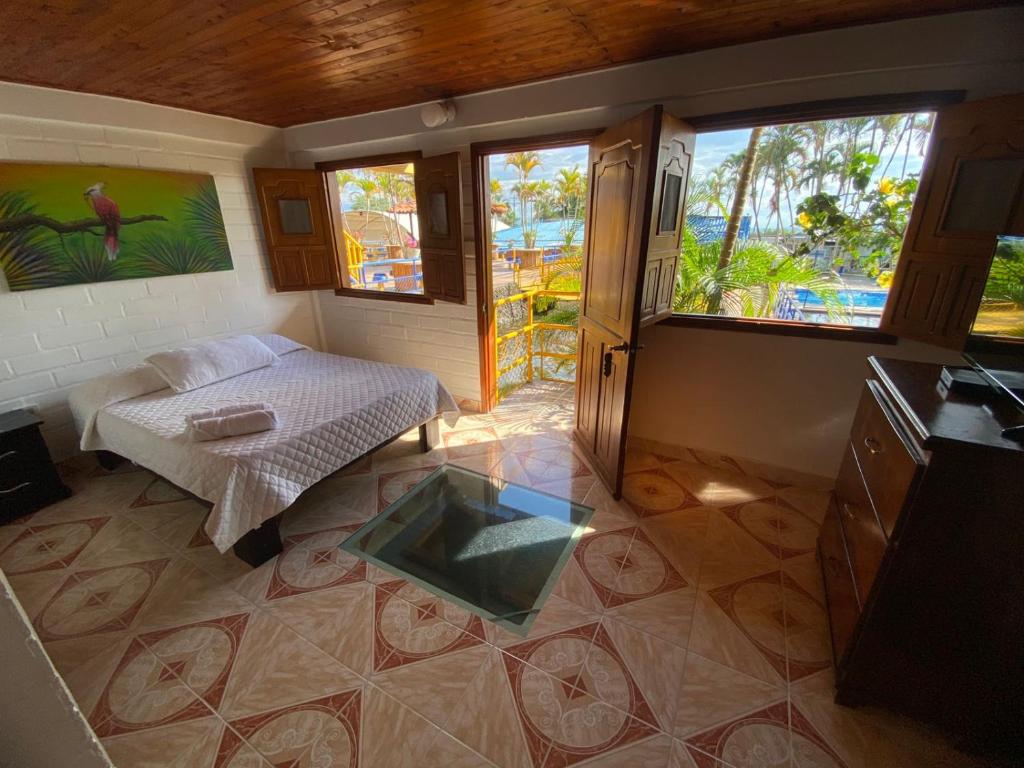 a room with a bed and a table and windows at Las Bailarinas Hotel Campestre in Montenegro