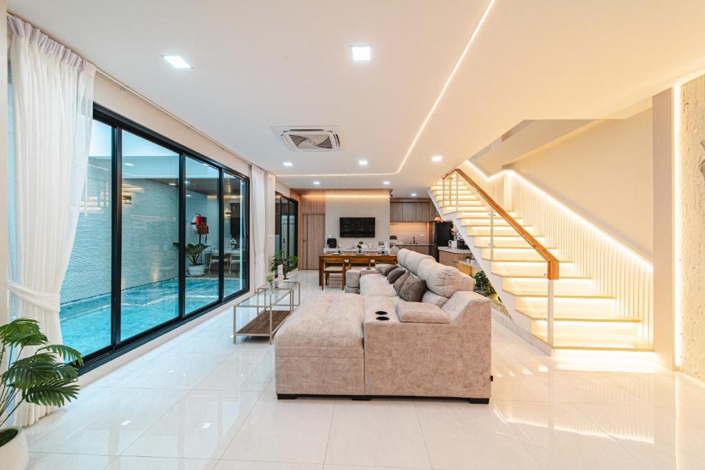 a living room with a couch and a staircase at Serene Pool Villa Pattaya 2 in Pattaya