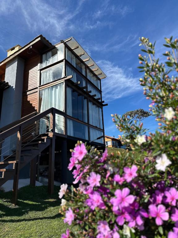 a house with glass windows and pink flowers at Chalé dos Manacás Duplex in Venda Nova do Imigrante