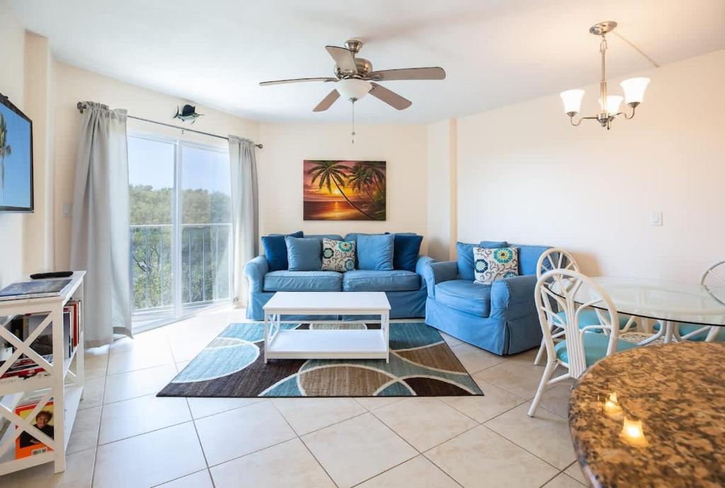 a living room with a blue couch and a table at Keys Waterfront Condo with Beach Pool Sunset Views in Tavernier