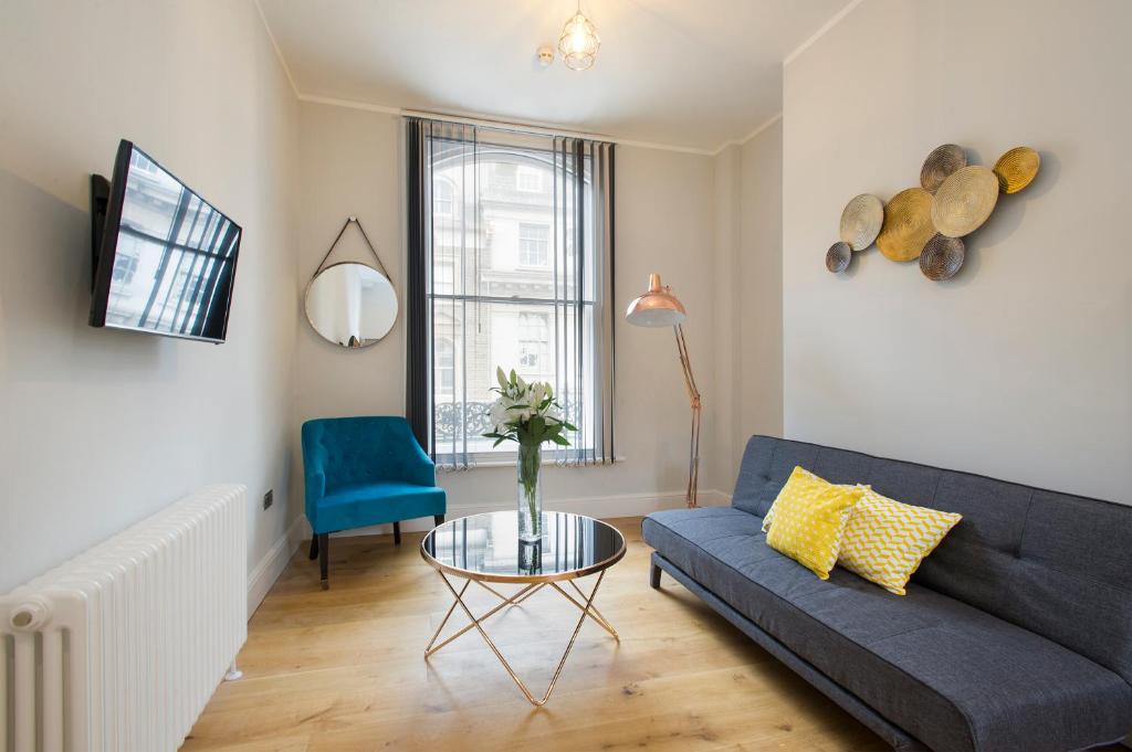 a living room with a blue couch and a table at Market Street Apartments - City Centre Modern 1bedroom Apartments with NEW WIFI and Very Close to Tram in Nottingham