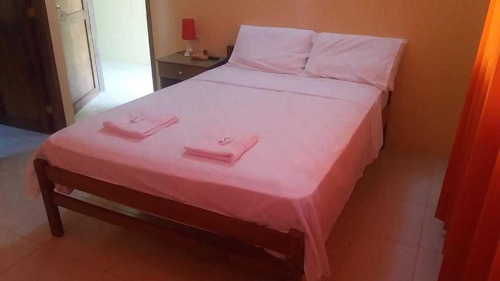 un letto con due asciugamani rosa sopra di Hostal Montecarlos a Salinas