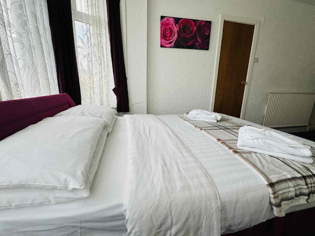 a white bed in a bedroom with roses on the wall at Ride Side Delton Hotel in Blackpool