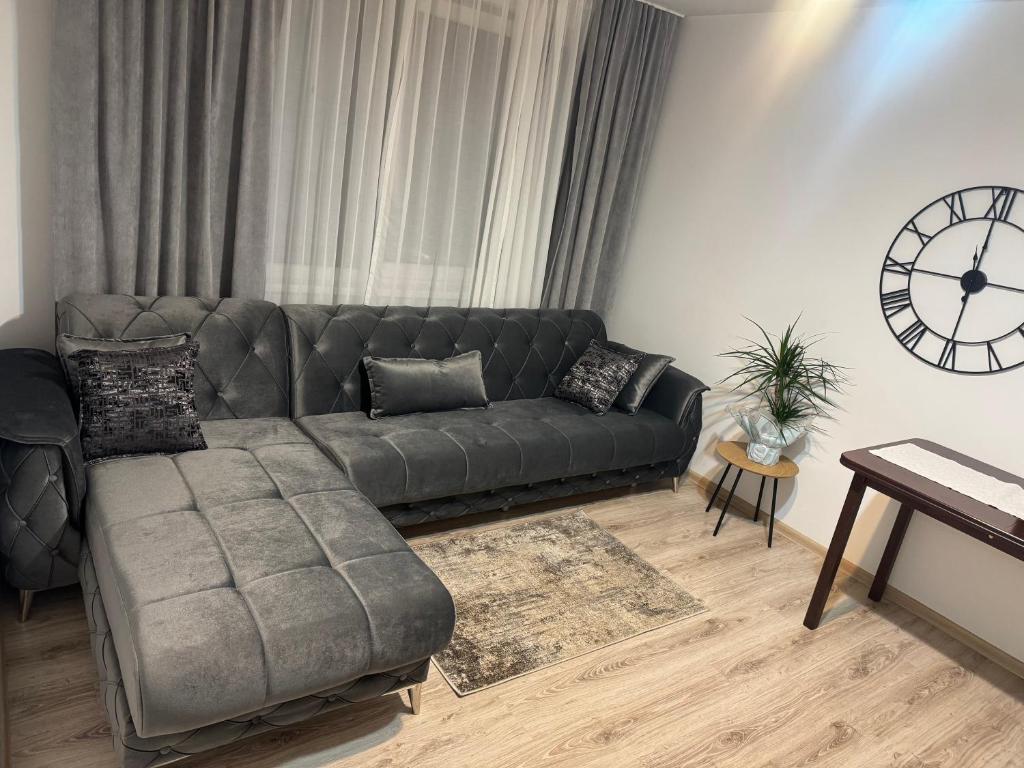 a couch in a living room with a clock on the wall at Apartament Central Pietonalul Unirii in Botoşani