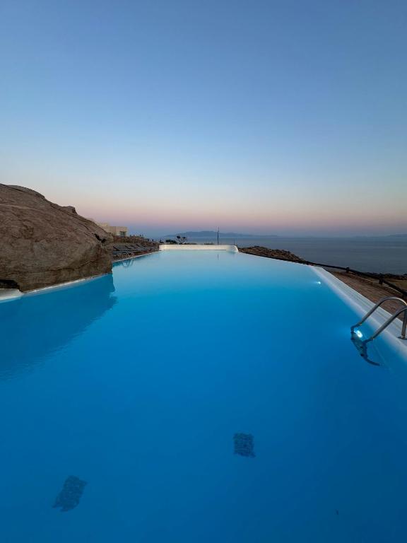 a blue pool with the ocean in the background at Orama suite I in Mikonos
