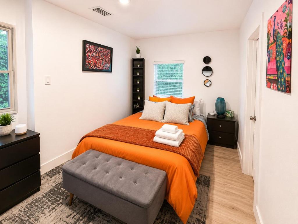 a bedroom with a bed with an orange bedspread at Quiet & Centrally located House - PRIVATE PARKING, LAUNDRY AND STORAGE FOR LUGGAGE in Miami