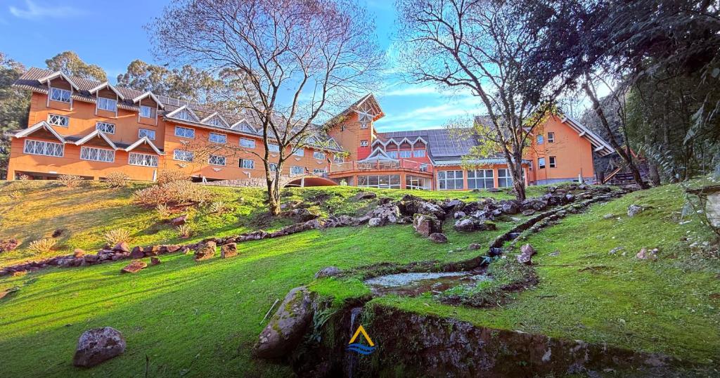 a large house on a grassy hill with a house at Hotel Renascença By Rede Elevare in Gramado