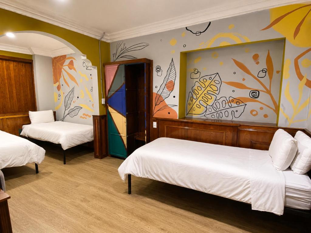 a room with two beds and a painting on the wall at Cavi Rooms 305 in Cuenca