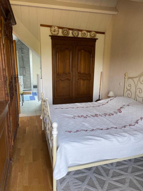 a bedroom with a white bed with a wooden headboard at Le balcon in Beaumont-le-Hareng