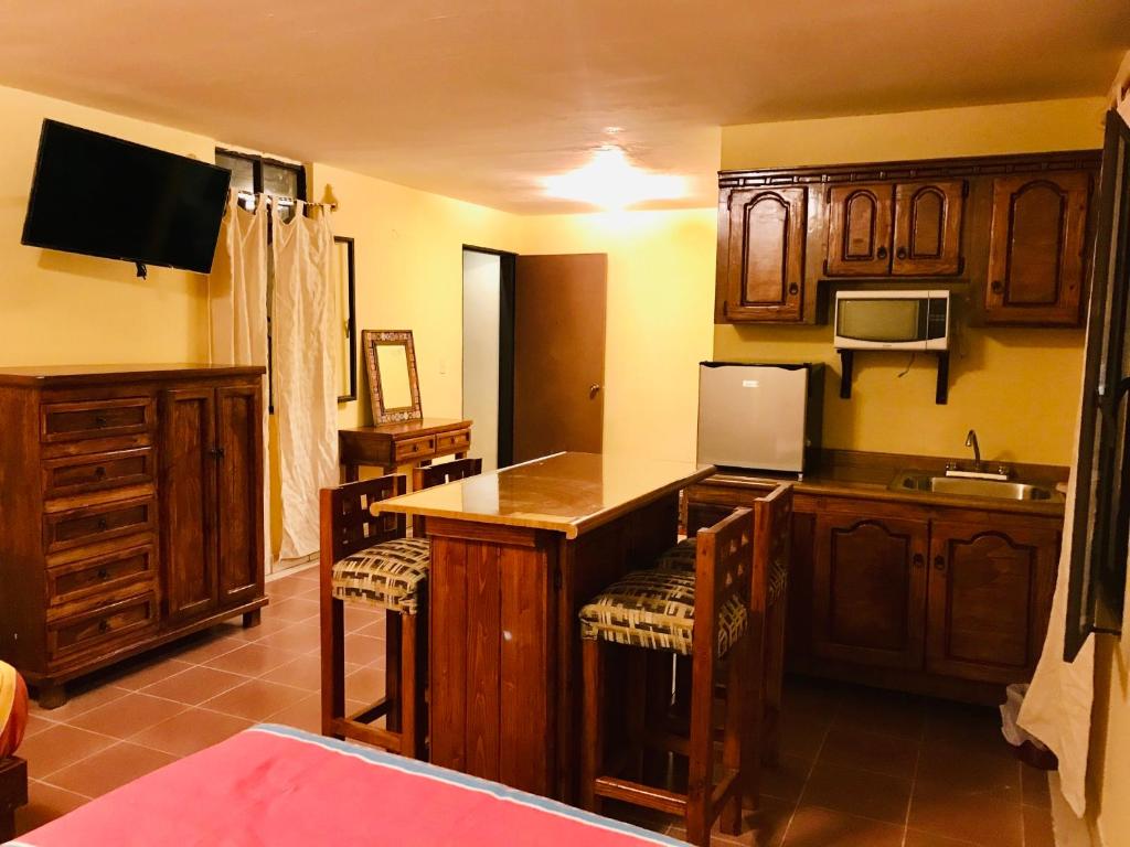a kitchen with wooden cabinets and a counter with chairs at Hotel Departamentos Suites in Guanajuato