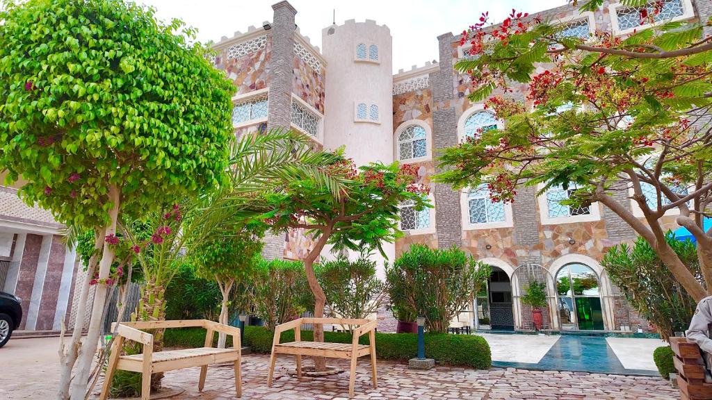 a building with two chairs and trees in front of it at Hôtel Résidence le Berger in Nouakchott