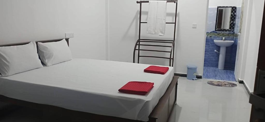 a bedroom with a bed with two red towels on it at Sivas friendly guest house in Nilaveli