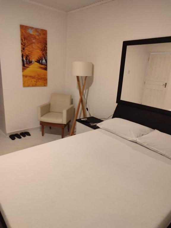 a bedroom with a white bed and a chair at Motel Hotel Le Premier in Venâncio Aires