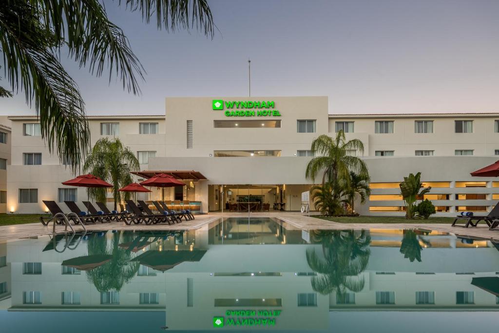 un hôtel avec une piscine en face d'un bâtiment dans l'établissement Wyndham Garden Playa del Carmen, à Playa del Carmen