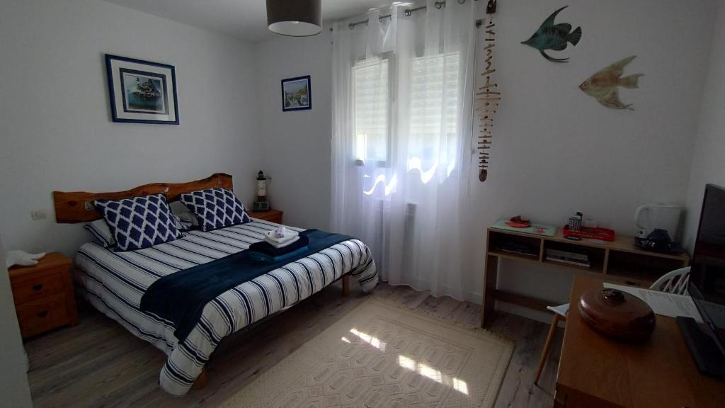 a bedroom with a bed and a desk and a window at L'écrin d'Ar Prajou in Plouénan