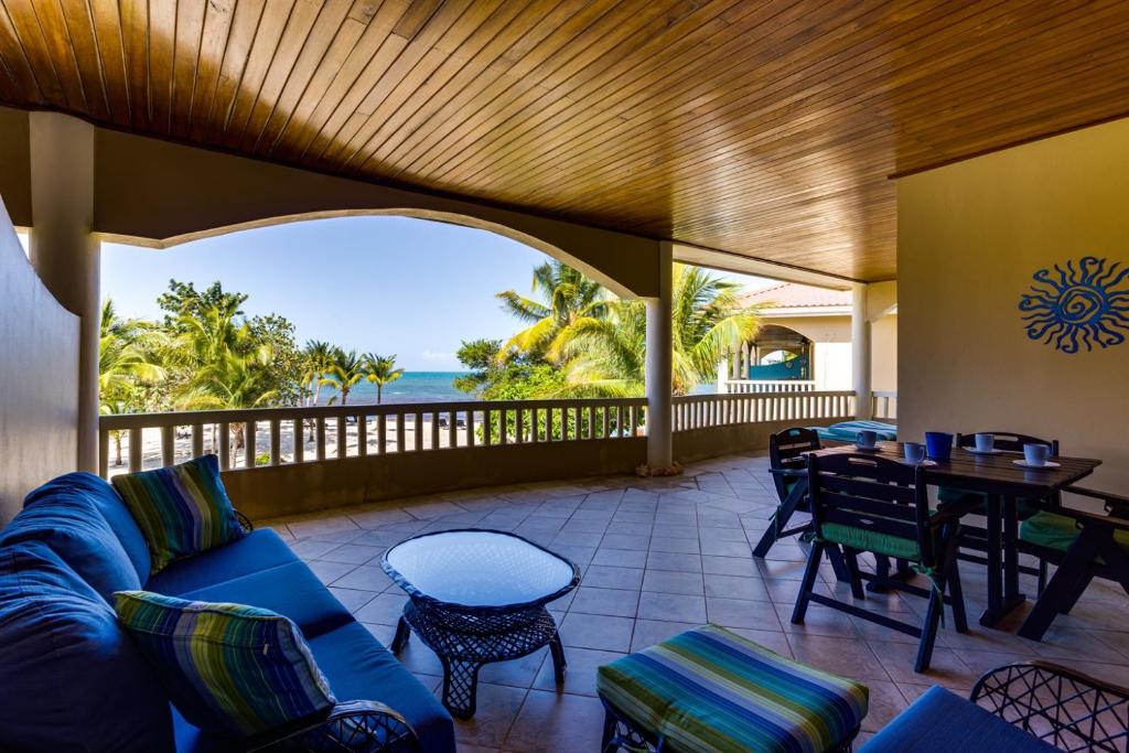 an outdoor patio with a blue couch and a table and chairs at Beachfront 2BR Villa with Pool & Spacious Layout in Placencia