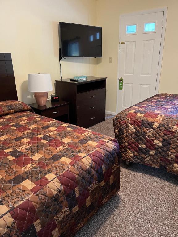 a hotel room with two beds and a flat screen tv at McGregor Inn Motel in Saratoga Springs