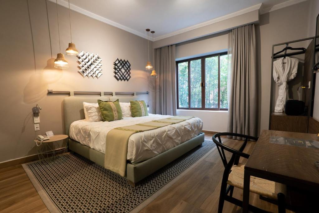 A warmly decorated bedroom with a king-size bed, desk and leafy window view.