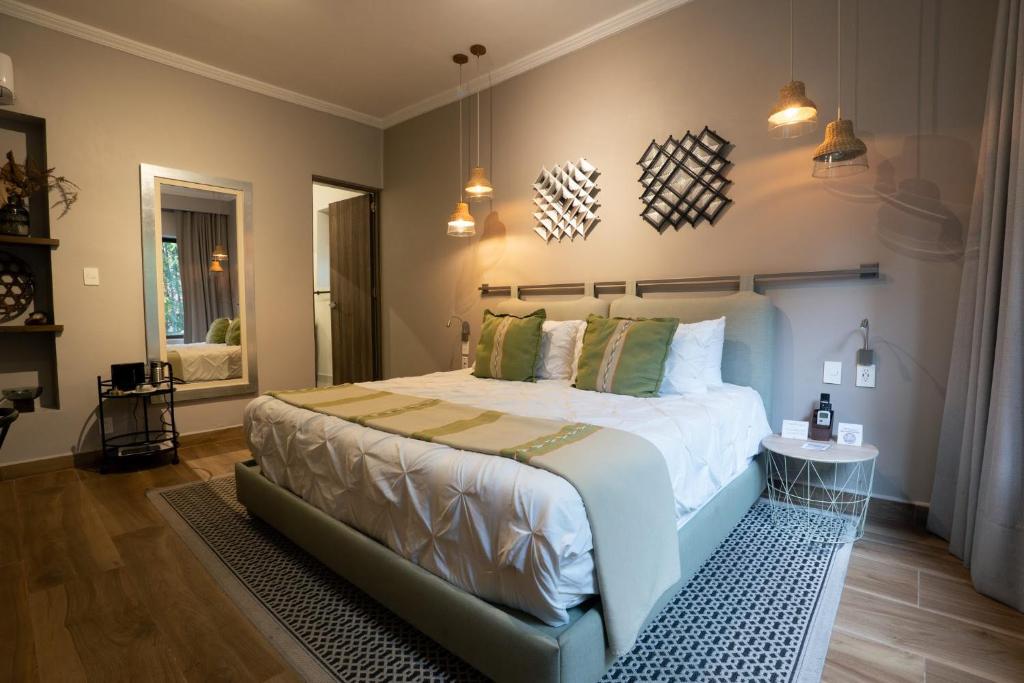 A design-focused bedroom has a large white bed, green accents, and a curtained window.