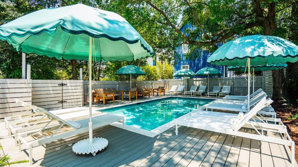 a swimming pool with two umbrellas and lounge chairs at The Iris in Charleston