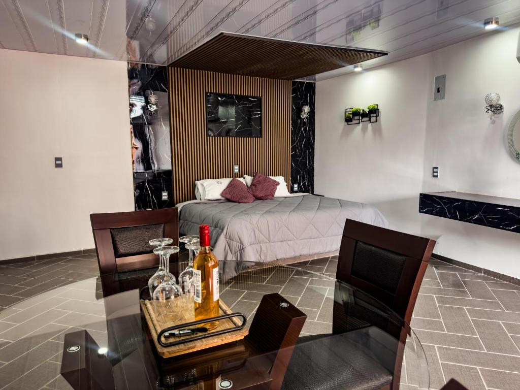 a bedroom with a bed and a table with a bottle of wine at Suites de Luxe en Hotel in Cuetzalán del Progreso