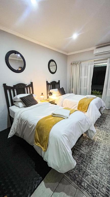 a bedroom with two beds and a mirror on the wall at Nestled Peace in Klerksdorp