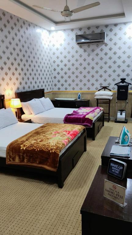 a room with three beds and a table with a piano at Hotel The Shalimar in Lahore