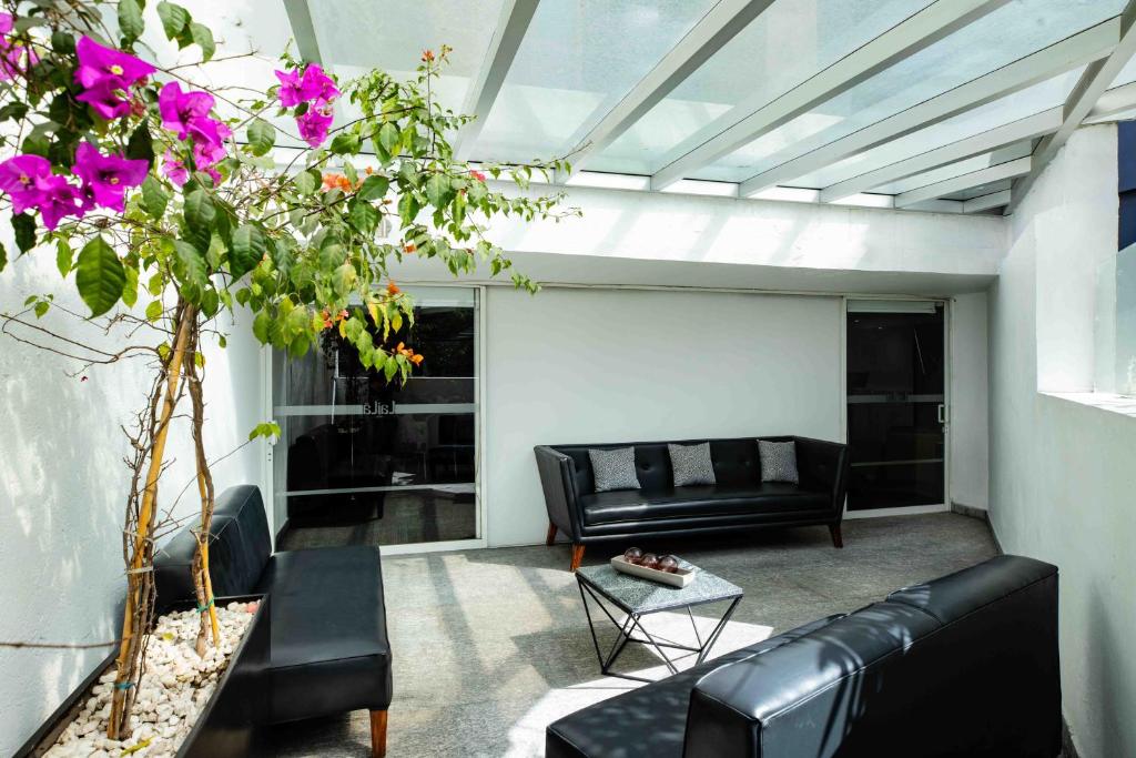 A bright glass-roofed lounge with black leather sofas and a coffee table.