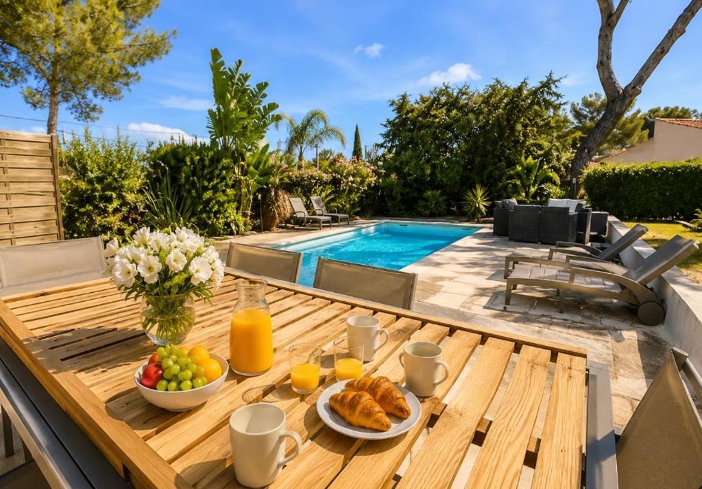 a wooden table with breakfast foods on it next to a pool at Haut de Villa Bianca - Spacious - Quiet in Saint-Raphaël