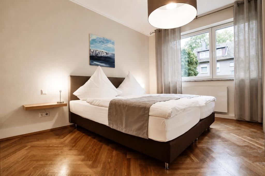 a bedroom with a bed with white sheets and a large window at Kampowski Apartments Bad Nauheim in Bad Nauheim
