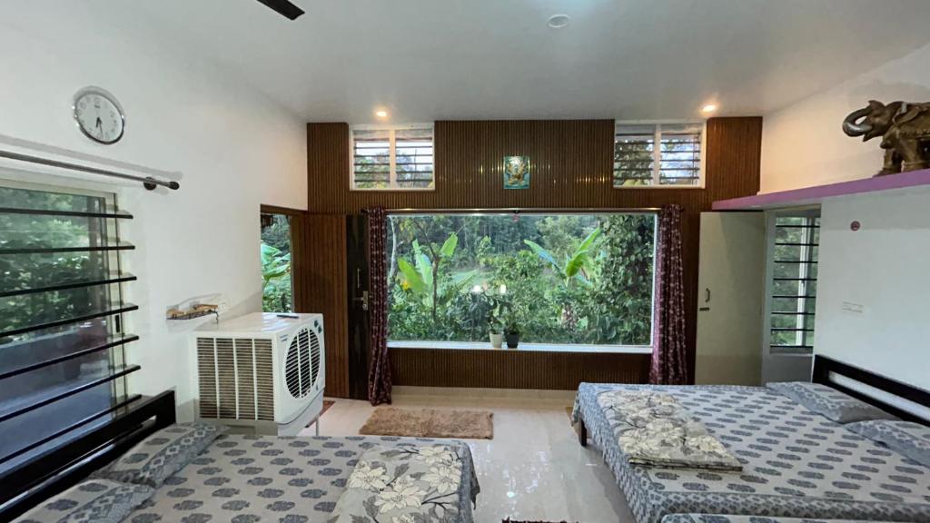 a bedroom with two beds and a large window at Doddakallu Betta Homestay Coorg in Somvārpet