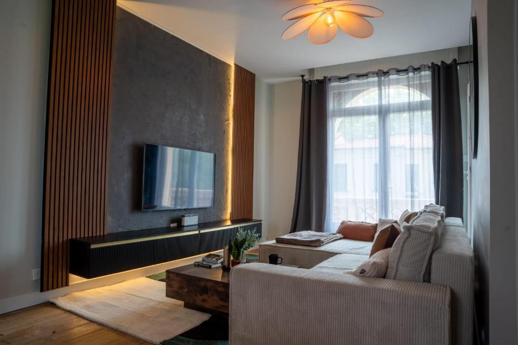 a living room with a couch and a tv at 1 Peraudel Suite & Appartements in Castres