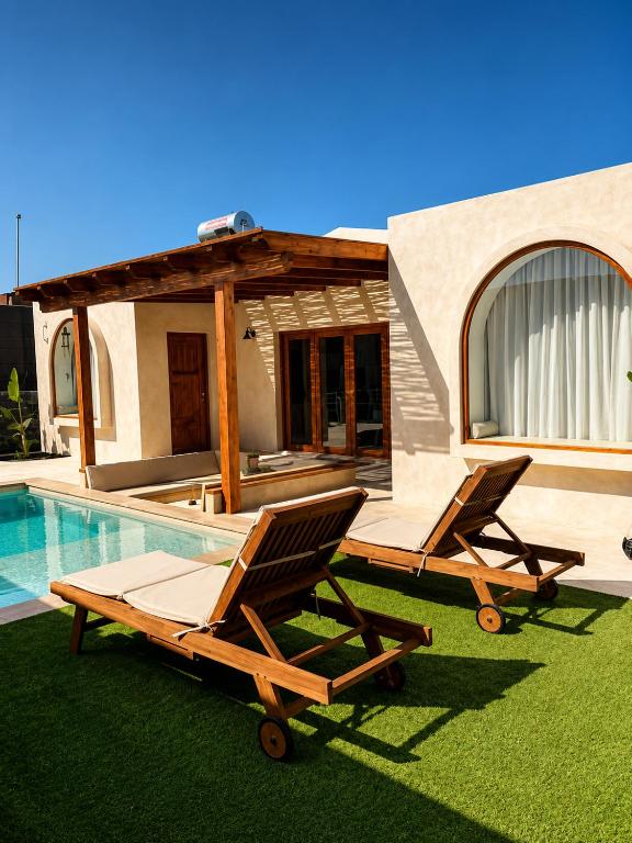 two lounge chairs on the grass next to a swimming pool at Villa Majora - Piscina climatizada in Tuineje