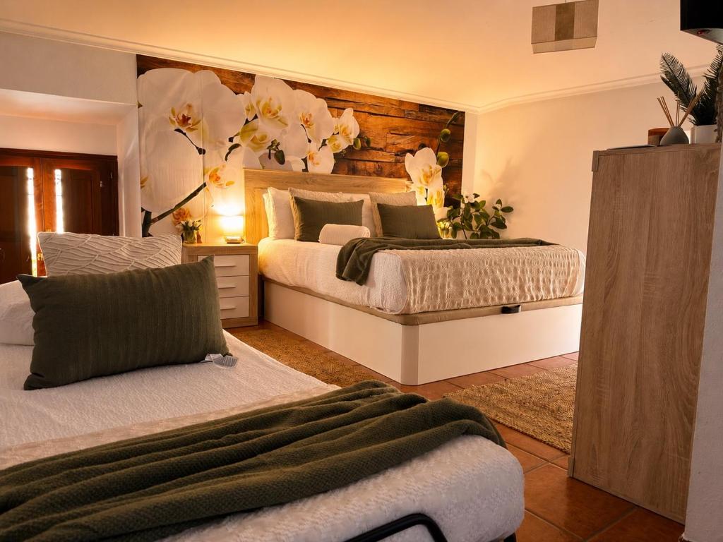 a bedroom with two beds and flowers on the wall at Casa El Rubio in San Vicente de la Sonsierra
