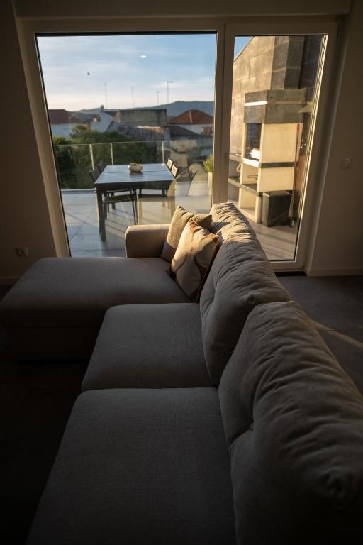 a couch in a living room with a large window at Douro River Apartment in Vila Nova de Foz Coa