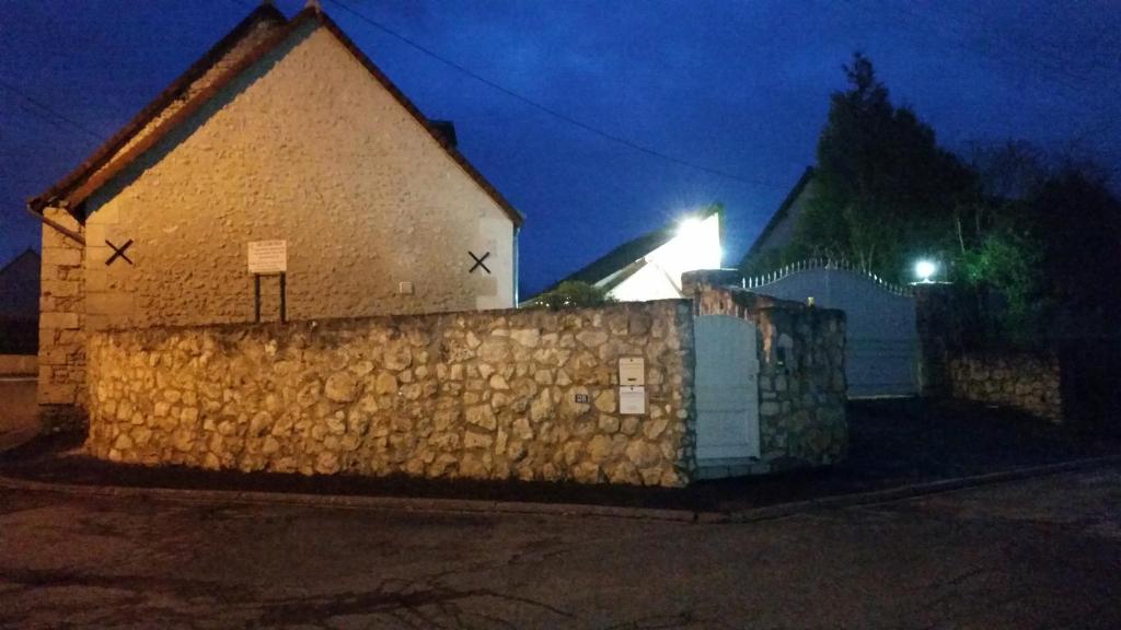 une clôture en pierre devant un bâtiment la nuit dans l'établissement Le Clos des Alouettes, à Amboise