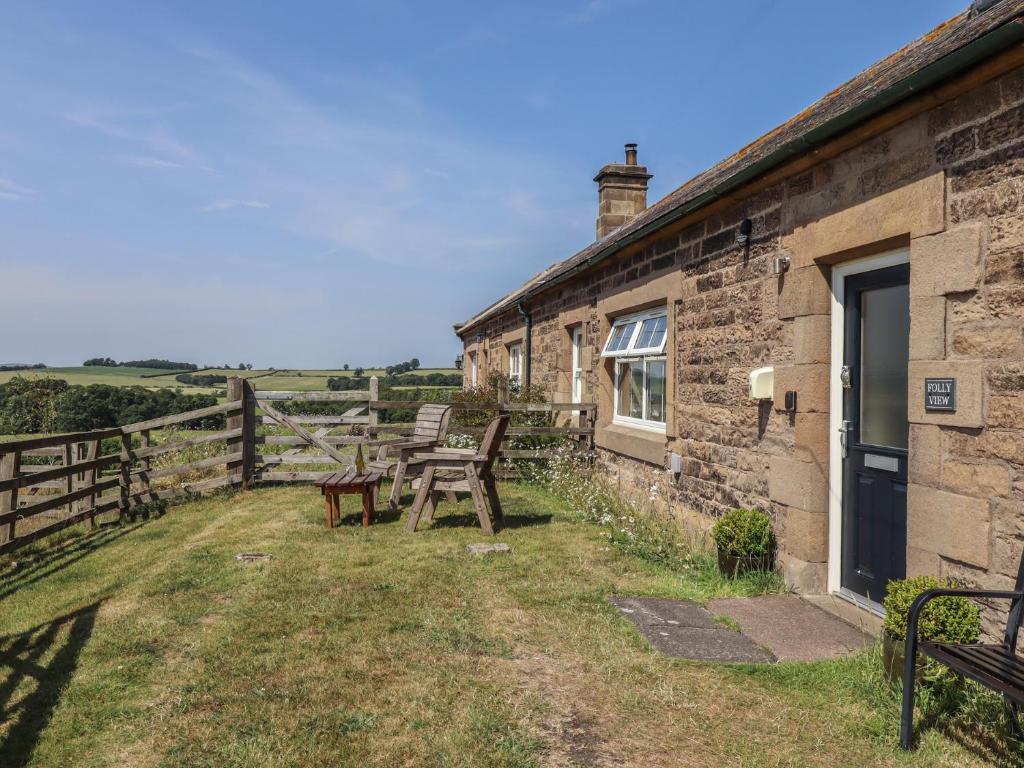 a farmhouse with a table and benches outside of it at Folly View in Alnwick