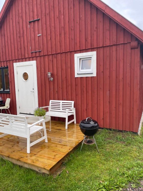 ein Grill auf einer Holzterrasse neben einem roten Gebäude in der Unterkunft Room 1 in Hästveda