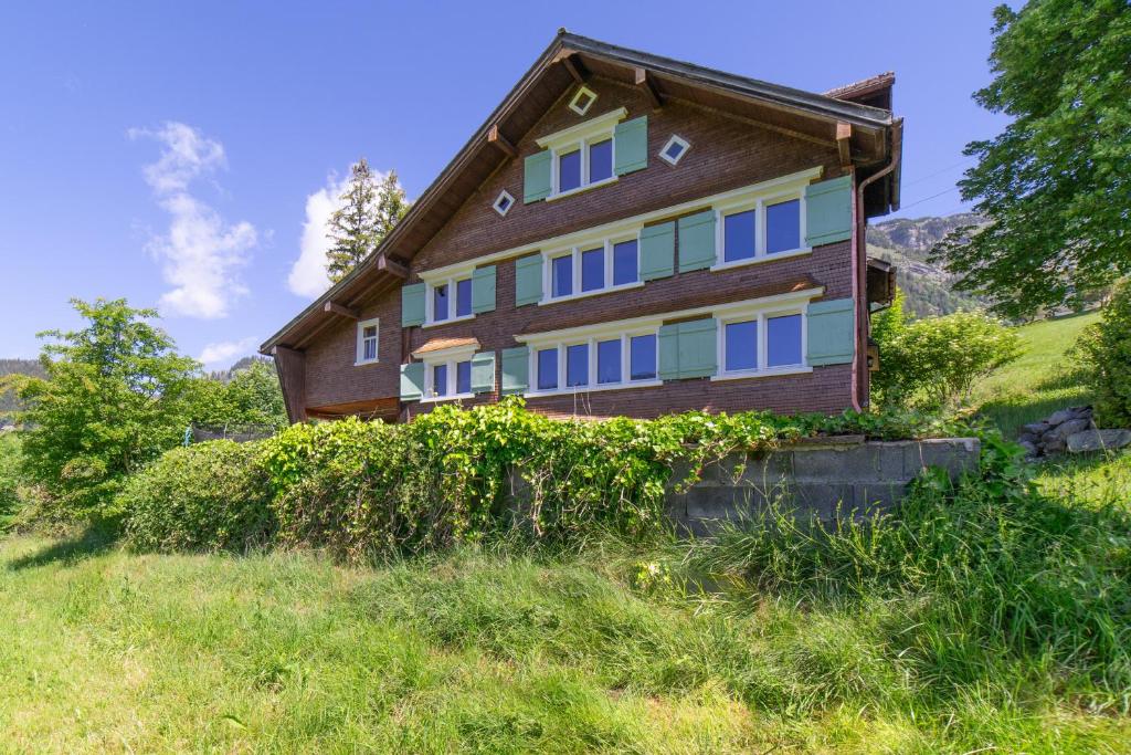 a house with blue windows on a hill at Sigerst in Wildhaus