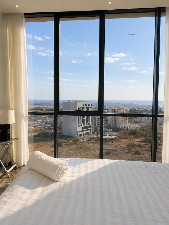 a bedroom with a white bed and a large window at Travellers Deluxe Apartment in Muscat