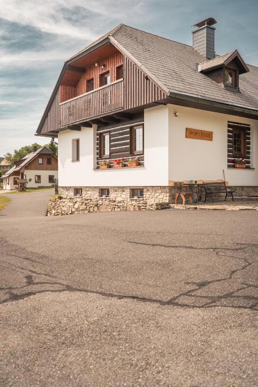 a white house with a wooden roof on a street at Penzion U Andresů in Zadov