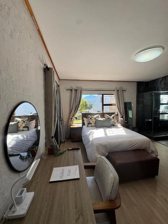 a bedroom with a bed and a mirror and a table at Hidden Gem in George