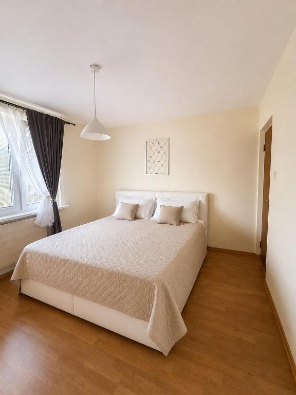 a white bedroom with a large white bed with pillows at Apartnám Harmony in Martin