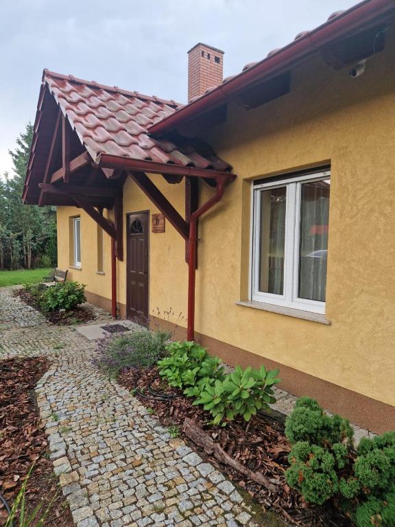 a house with a brick walkway next to a building at Lawendowa Ostoja - dom na wyłączność in Uście