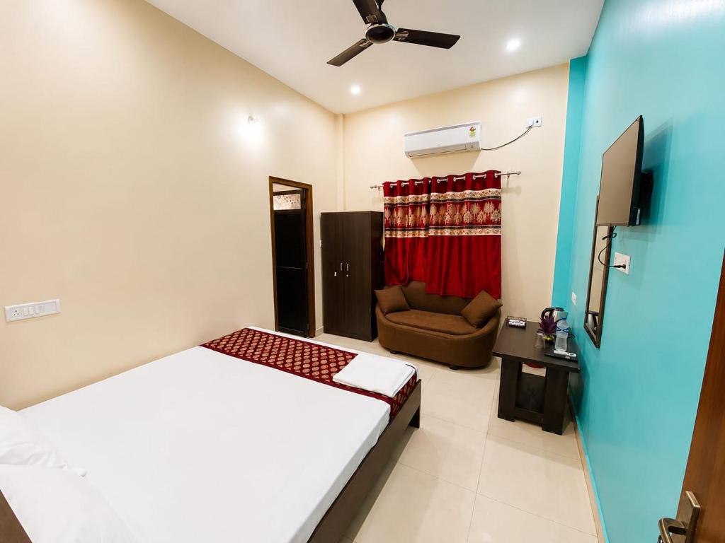 a bedroom with a bed and a couch and a ceiling fan at Hotel Vindhwasni Palace in Sītāmarhi