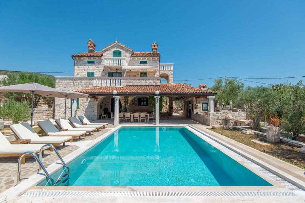 a villa with a swimming pool in front of a house at Villa Rustica - Veslo in Begovići