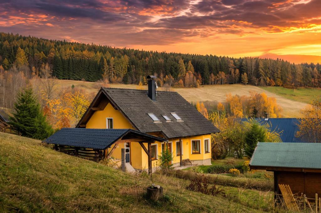 a house on a hill with a sunset in the background at Sluneční stráň - dům pro 9 osob in Dolni Dvur