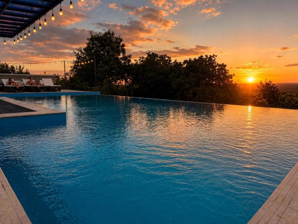 a large swimming pool with a sunset in the background at Villaggio Mirzaani Resort in Sighnaghi